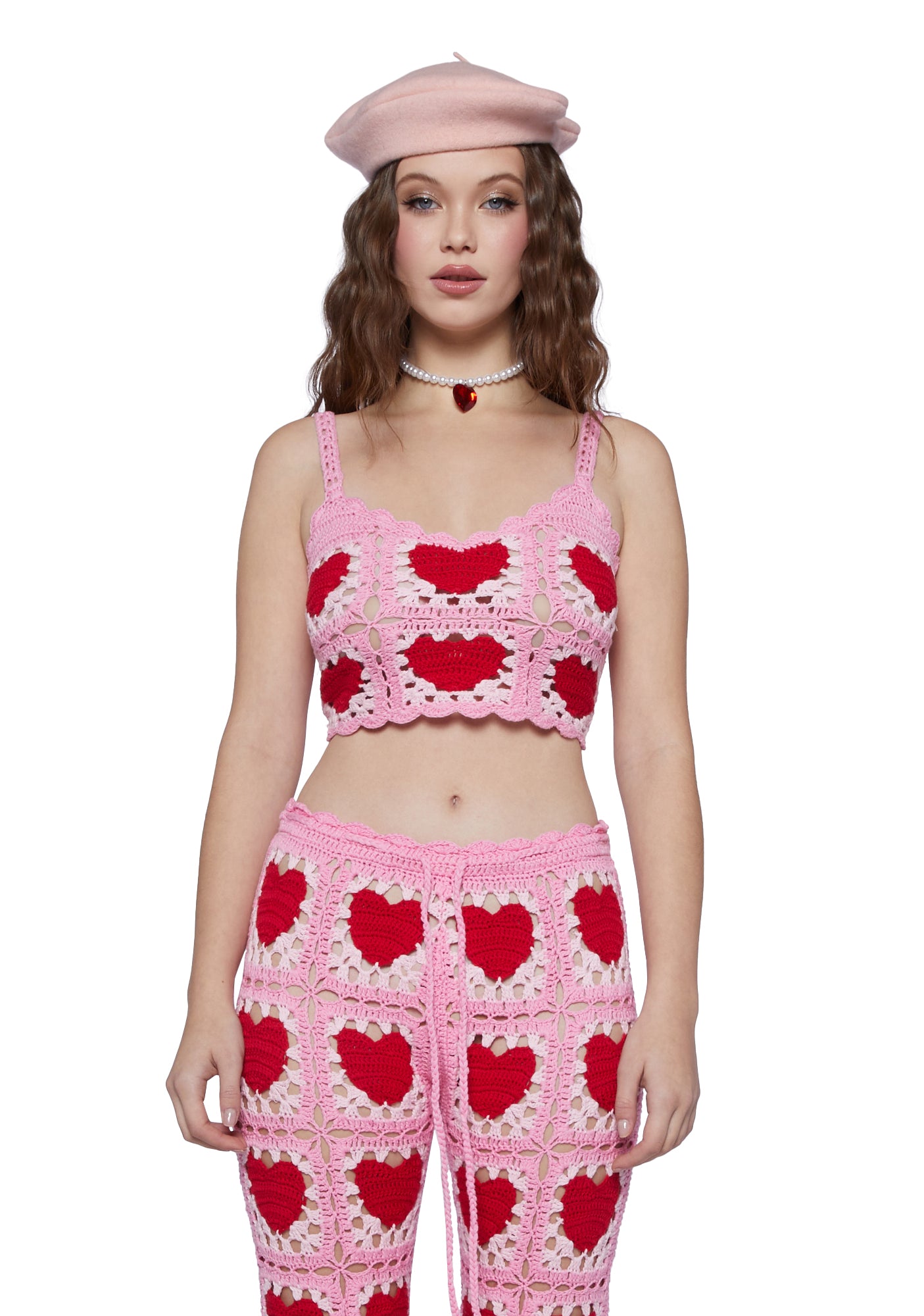 a woman wearing a crochet pink and red heart crop top and pants